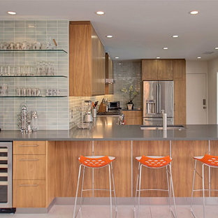 Inspiration for a midcentury l-shaped eat-in kitchen in Los Angeles with flat-panel cabinets, medium wood cabinets, grey splashback, subway tile splashback, stainless steel appliances, concrete floors and a peninsula.