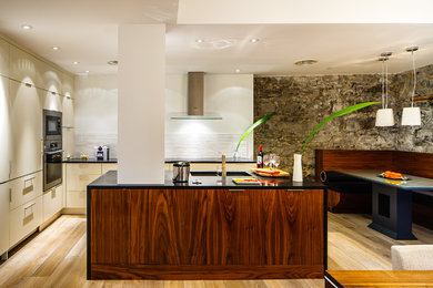 Example of a trendy eat-in kitchen design in Montreal with flat-panel cabinets, beige cabinets and paneled appliances