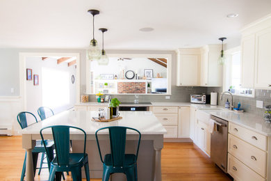 Große Klassische Wohnküche in L-Form mit Landhausspüle, Schrankfronten im Shaker-Stil, weißen Schränken, Rückwand aus Keramikfliesen, Küchengeräten aus Edelstahl, braunem Holzboden und Kücheninsel in Boston