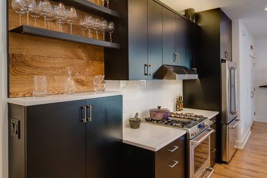 Example of a mid-sized trendy galley medium tone wood floor eat-in kitchen design in Other with an undermount sink, recessed-panel cabinets, dark wood cabinets, quartz countertops, white backsplash, glass sheet backsplash, stainless steel appliances and an island