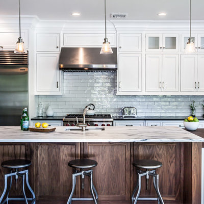 Example of a cottage l-shaped kitchen design in New York with an undermount sink, shaker cabinets, white cabinets, white backsplash, subway tile backsplash, stainless steel appliances and an island