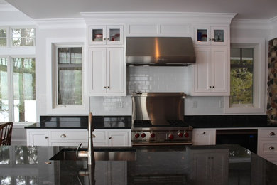 ミルウォーキーにある広いトラディショナルスタイルのおしゃれなキッチン (アンダーカウンターシンク、落し込みパネル扉のキャビネット、白いキャビネット、御影石カウンター、白いキッチンパネル、セラミックタイルのキッチンパネル、シルバーの調理設備) の写真