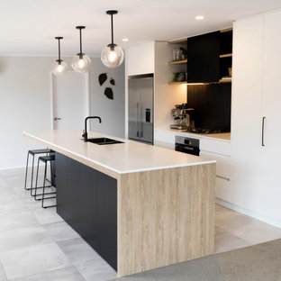 This is an example of a mid-sized scandinavian galley eat-in kitchen in Other with a double-bowl sink, flat-panel cabinets, black cabinets, solid surface benchtops, black splashback, mosaic tile splashback, stainless steel appliances, porcelain floors, with island, grey floor and white benchtop.