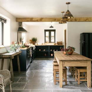 Imagen de cocina comedor en L, de estilo de casa de campo, de tamaño medio, sin isla, con fregadero sobremueble, armarios estilo shaker, puertas de armario azules, encimera de madera, electrodomésticos de acero inoxidable y suelo de piedra caliza