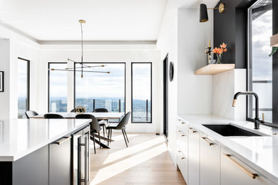 Inspiration for a contemporary light wood floor kitchen remodel in Vancouver with an undermount sink, flat-panel cabinets, black cabinets, quartz countertops, white backsplash, quartz backsplash, paneled appliances, an island and white countertops