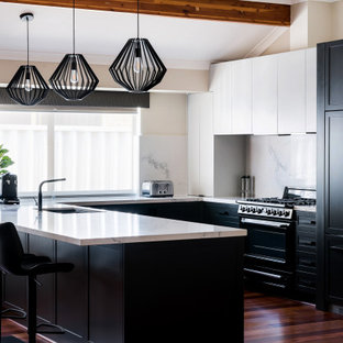 Design ideas for a transitional u-shaped kitchen in Perth with an undermount sink, shaker cabinets, black cabinets, white splashback, stone slab splashback, black appliances, dark hardwood floors, a peninsula, brown floor, white benchtop and vaulted.