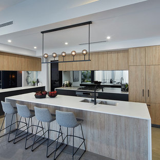 Photo of a contemporary l-shaped kitchen in Perth with a double-bowl sink, flat-panel cabinets, light wood cabinets, mirror splashback, black appliances, with island, beige floor and white benchtop.