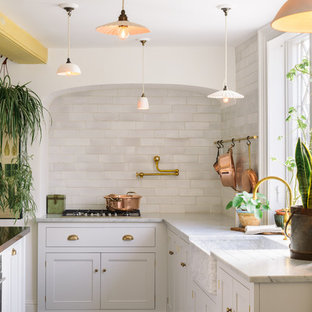 Design ideas for a large shabby-chic style eat-in kitchen in Other with a farmhouse sink, shaker cabinets, white cabinets, marble benchtops, white splashback, subway tile splashback, panelled appliances, terra-cotta floors, with island and brown floor.