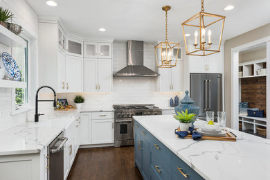 Example of a large transitional l-shaped dark wood floor and brown floor open concept kitchen design in Chicago with a farmhouse sink, shaker cabinets, white cabinets, quartzite countertops, white backsplash, subway tile backsplash, stainless steel appliances, an island and white countertops
