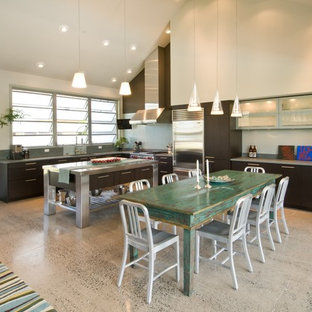 Modelo de cocina en L, exótica, abierta, con armarios con paneles lisos, electrodomésticos de acero inoxidable y puertas de armario de madera en tonos medios