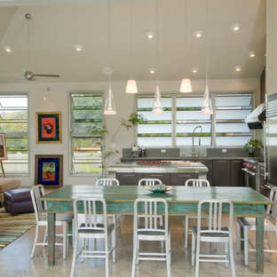 Imagen de cocina en L, tropical, abierta, con electrodomésticos de acero inoxidable, armarios con paneles lisos y puertas de armario de madera en tonos medios