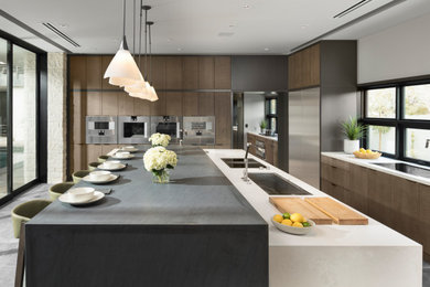 Huge trendy l-shaped porcelain tile and gray floor open concept kitchen photo in Las Vegas with an undermount sink, flat-panel cabinets, quartz countertops, stainless steel appliances, an island, white countertops, medium tone wood cabinets and window backsplash