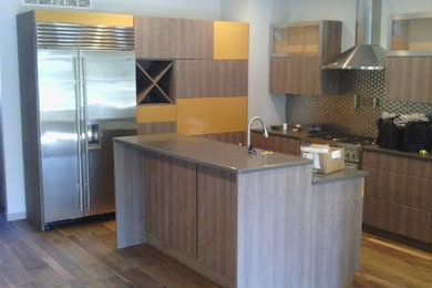 Example of a trendy kitchen design in Cleveland with flat-panel cabinets, stainless steel appliances and an island