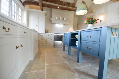 Large farmhouse u-shaped open plan kitchen in Sussex with beaded cabinets, beige cabinets, quartz worktops, white splashback, integrated appliances, limestone flooring, an island, white worktops, an integrated sink and green floors.