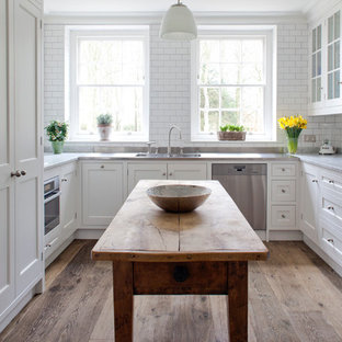 Photo of a traditional u-shaped separate kitchen in Wiltshire with recessed-panel cabinets, white cabinets, marble benchtops, white splashback, subway tile splashback and stainless steel appliances.