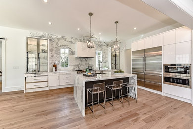 Photo of a contemporary u-shaped kitchen/diner in Charlotte with a submerged sink, flat-panel cabinets, white cabinets, marble worktops, white splashback, marble splashback, stainless steel appliances, light hardwood flooring, an island and beige floors.