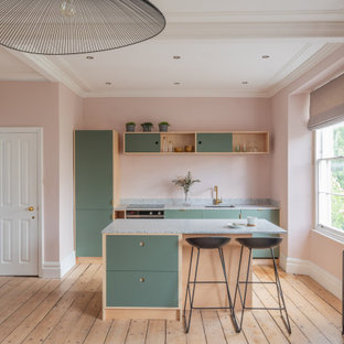 Scandi galley kitchen in Other with a submerged sink, flat-panel cabinets, green cabinets, stainless steel appliances, light hardwood flooring, beige floors and grey worktops.