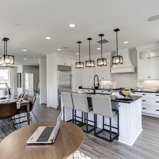 Large transitional open plan kitchen in DC Metro with an undermount sink, shaker cabinets, white cabinets, granite benchtops, grey splashback, ceramic splashback, stainless steel appliances, vinyl floors, with island, grey floor and black benchtop.
