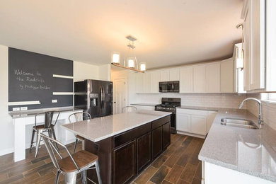 Example of a mid-sized transitional u-shaped porcelain tile and brown floor kitchen design in Chicago with a double-bowl sink, shaker cabinets, white cabinets, white backsplash, subway tile backsplash, stainless steel appliances, an island and gray countertops