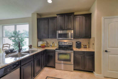 Example of a mid-sized transitional u-shaped ceramic tile kitchen design in Austin with a double-bowl sink, raised-panel cabinets, dark wood cabinets, granite countertops, beige backsplash, stone slab backsplash, stainless steel appliances and a peninsula