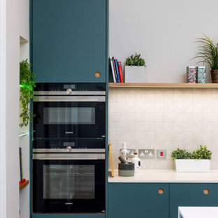 Photo of a mid-sized contemporary single-wall open plan kitchen in Other with an undermount sink, flat-panel cabinets, blue cabinets, quartzite benchtops, white splashback, stainless steel appliances, medium hardwood floors, with island, brown floor, white benchtop and porcelain splashback.