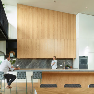 Design ideas for a contemporary galley eat-in kitchen in Brisbane with an integrated sink, flat-panel cabinets, medium wood cabinets, grey splashback, stone slab splashback, coloured appliances, medium hardwood floors, with island, brown floor and grey benchtop.