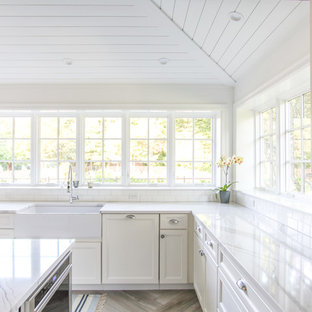 Large coastal eat-in kitchen appliance - Inspiration for a large coastal u-shaped porcelain tile and gray floor eat-in kitchen remodel in New York with a farmhouse sink, shaker cabinets, white cabinets, quartz countertops, white backsplash, subway tile backsplash, paneled appliances, an island and white countertops