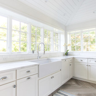 Large coastal eat-in kitchen ideas - Large beach style u-shaped porcelain tile and gray floor eat-in kitchen photo in New York with a farmhouse sink, shaker cabinets, white cabinets, quartz countertops, white backsplash, subway tile backsplash, paneled appliances, an island and white countertops