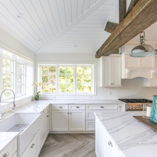 Large coastal eat-in kitchen appliance - Inspiration for a large coastal u-shaped porcelain tile and gray floor eat-in kitchen remodel in New York with a farmhouse sink, shaker cabinets, white cabinets, quartz countertops, white backsplash, subway tile backsplash, paneled appliances, an island and white countertops