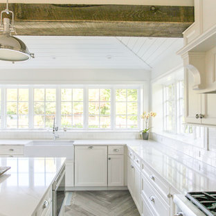Large coastal eat-in kitchen ideas - Large beach style u-shaped porcelain tile and gray floor eat-in kitchen photo in New York with a farmhouse sink, shaker cabinets, white cabinets, quartz countertops, white backsplash, subway tile backsplash, paneled appliances, an island and white countertops