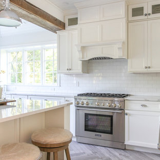 Large coastal eat-in kitchen designs - Eat-in kitchen - large coastal u-shaped porcelain tile and gray floor eat-in kitchen idea in New York with a farmhouse sink, shaker cabinets, white cabinets, quartz countertops, white backsplash, subway tile backsplash, paneled appliances, an island and white countertops