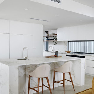 Photo of a contemporary kitchen in Perth with an undermount sink, flat-panel cabinets, white cabinets, solid surface benchtops, black appliances, travertine floors, with island, beige floor and multi-coloured benchtop.