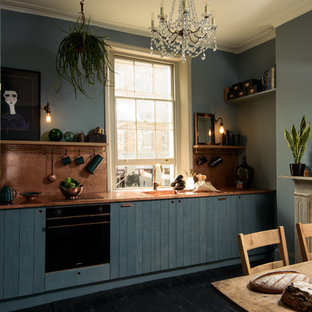 Foto di una cucina abitabile moderna di medie dimensioni con lavello integrato, ante lisce, ante blu, top in rame, paraspruzzi arancione, elettrodomestici da incasso, pavimento in legno verniciato, nessuna isola e pavimento nero