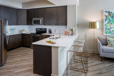 Open concept kitchen - mid-sized modern u-shaped vinyl floor and brown floor open concept kitchen idea in Orlando with an undermount sink, flat-panel cabinets, dark wood cabinets, quartzite countertops, white backsplash, subway tile backsplash, stainless steel appliances and a peninsula
