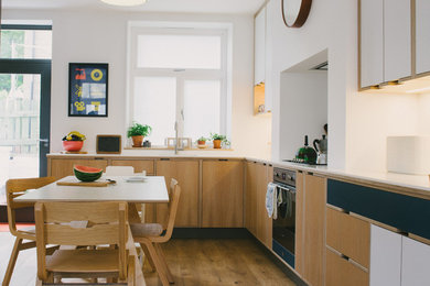 Photo of a medium sized contemporary l-shaped kitchen/diner in Other with a built-in sink, flat-panel cabinets, light wood cabinets, quartz worktops, white splashback, stone slab splashback, stainless steel appliances, light hardwood flooring and no island.