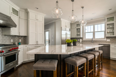 Eat-in kitchen - large traditional u-shaped dark wood floor and brown floor eat-in kitchen idea in Other with a drop-in sink, recessed-panel cabinets, white cabinets, quartz countertops, gray backsplash, subway tile backsplash, stainless steel appliances and an island