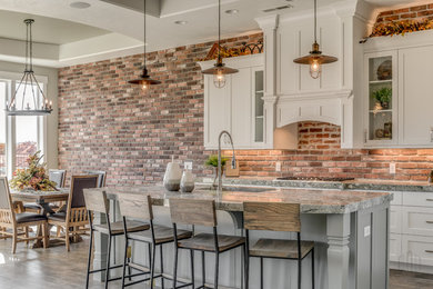 Inspiration for a large craftsman porcelain tile and brown floor eat-in kitchen remodel in Salt Lake City with an undermount sink, shaker cabinets, white cabinets, granite countertops, red backsplash, brick backsplash, stainless steel appliances, an island and multicolored countertops