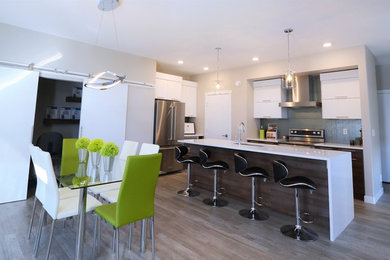 Eat-in kitchen - mid-sized contemporary l-shaped laminate floor and gray floor eat-in kitchen idea in Calgary with an undermount sink, flat-panel cabinets, white cabinets, quartzite countertops, gray backsplash, porcelain backsplash, stainless steel appliances and an island