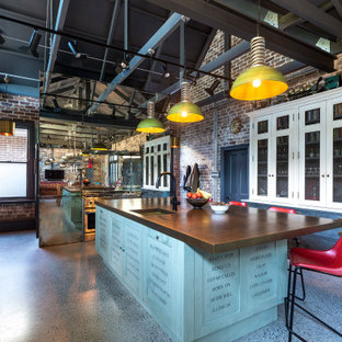 Inspiration for an expansive industrial u-shaped kitchen in Sydney with an undermount sink, glass-front cabinets, blue cabinets, brown splashback, brick splashback, stainless steel appliances, grey floor, brown benchtop and exposed beam.