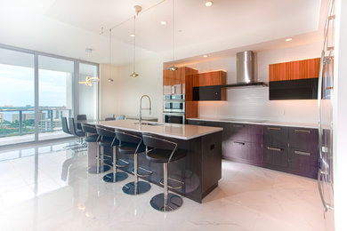 Eat-in kitchen - mid-sized contemporary white floor eat-in kitchen idea in Tampa with a drop-in sink, orange cabinets, white backsplash, stainless steel appliances, an island and white countertops