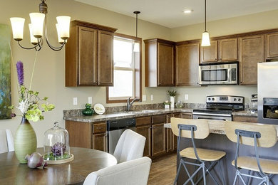 Mid-sized transitional medium tone wood floor eat-in kitchen photo in Minneapolis with a double-bowl sink, brown cabinets, stainless steel appliances and an island