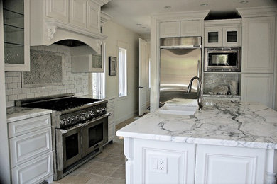 Exempel på ett mellanstort klassiskt kök, med en rustik diskho, luckor med upphöjd panel, vita skåp, marmorbänkskiva, vitt stänkskydd, stänkskydd i tunnelbanekakel, rostfria vitvaror och en köksö