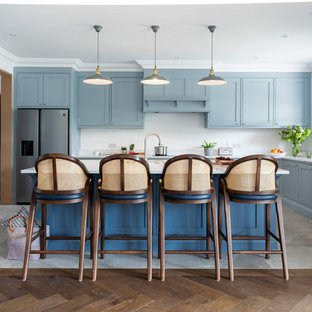 Inspiration for a large beach style u-shaped kitchen in Surrey with blue cabinets, quartzite benchtops, stainless steel appliances, ceramic floors, with island, white benchtop, shaker cabinets, white splashback and grey floor.