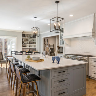 Large farmhouse eat-in kitchen remodeling - Large farmhouse l-shaped medium tone wood floor and brown floor eat-in kitchen photo in Other with a farmhouse sink, flat-panel cabinets, gray cabinets, quartzite countertops, white backsplash, ceramic backsplash, stainless steel appliances, an island and white countertops