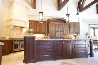 Example of a mid-sized classic travertine floor kitchen design in Houston with raised-panel cabinets, medium tone wood cabinets, granite countertops, beige backsplash, paneled appliances and an island