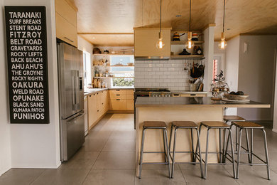 Réalisation d'une cuisine ouverte design en bois clair avec un placard à porte plane, une crédence blanche, une crédence en céramique, un électroménager en acier inoxydable, îlot, un sol gris et un plan de travail gris.