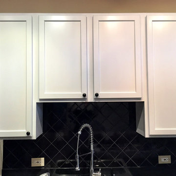 These custom bright white cabinets look great with the black backsplash