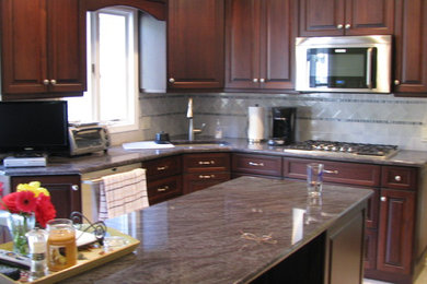 Inspiration for a timeless l-shaped eat-in kitchen remodel in Philadelphia with an undermount sink, raised-panel cabinets, dark wood cabinets, granite countertops, gray backsplash, ceramic backsplash and stainless steel appliances