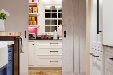 Photo of a rural kitchen in Boston with a belfast sink, beaded cabinets, blue cabinets, marble worktops, integrated appliances, light hardwood flooring and brown floors.