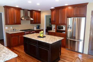 Example of a classic u-shaped medium tone wood floor eat-in kitchen design in Chicago with raised-panel cabinets, medium tone wood cabinets, granite countertops, multicolored backsplash, stone slab backsplash, stainless steel appliances and an island
